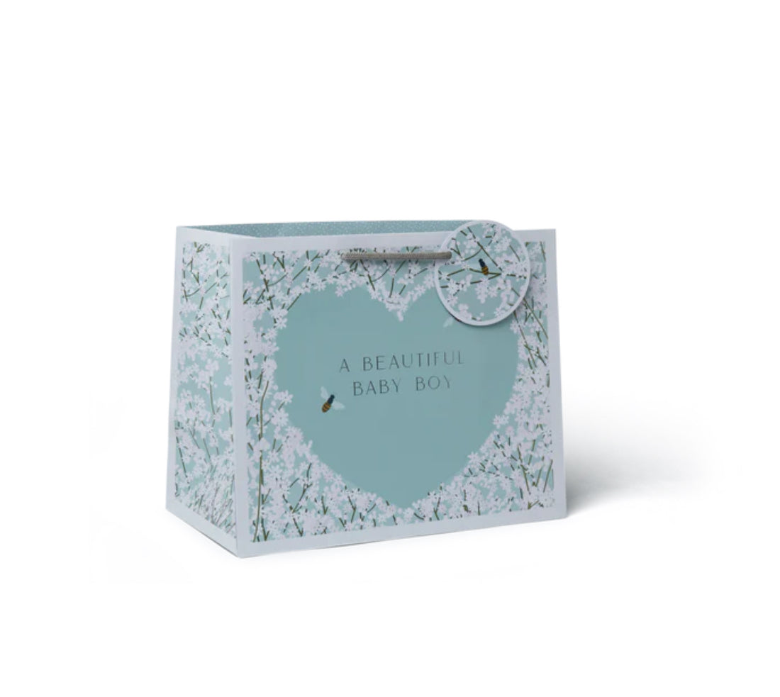 A blue and white woven paper tote bag with a handle and a gift tag that reads 'A beautiful baby boy'.