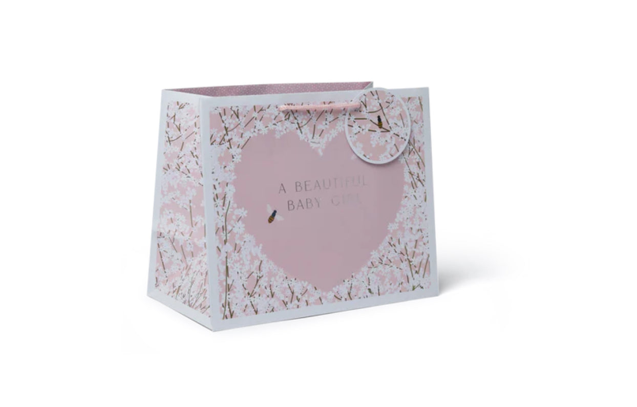 A pink floral-patterned tote bag with a woven paper handle and a gift tag that reads 'A real baby shower gift'.