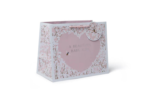 A pink floral-patterned tote bag with a woven paper handle and a gift tag that reads 'A real baby shower gift'.