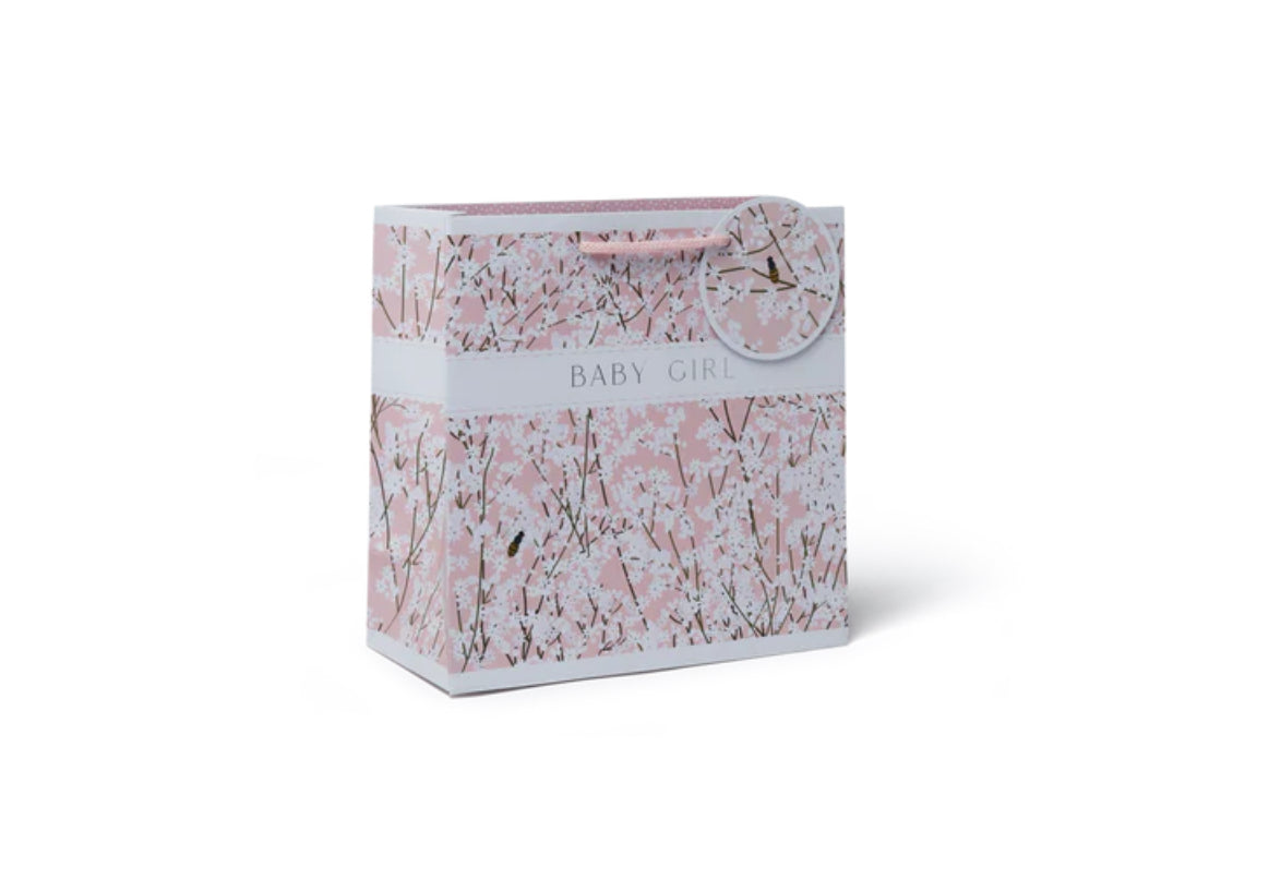 A medium-sized gift bag with a floral pattern, featuring a woven paper handle and a gift tag that reads 'Belly Girl'.