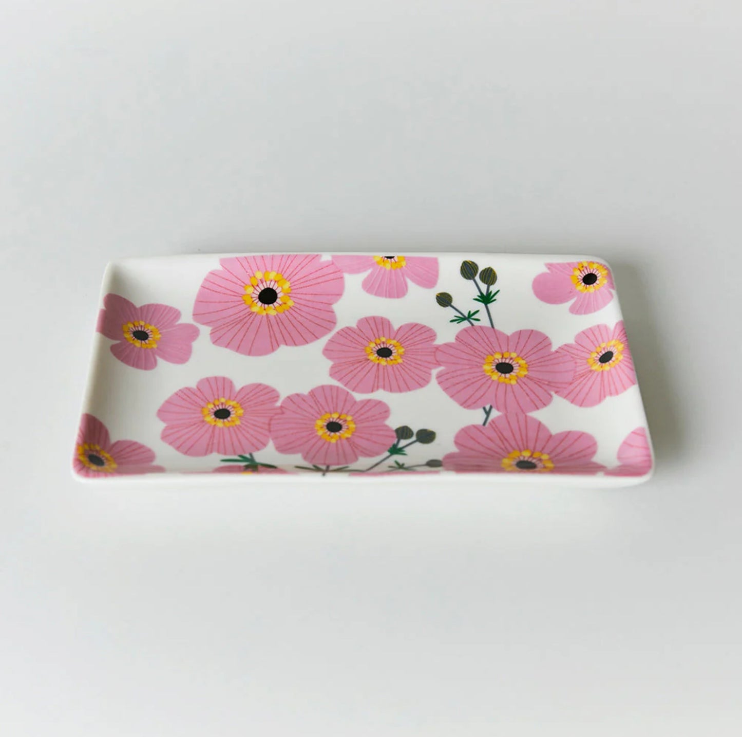 A rectangular pink trinket dish with a floral pattern of cosmos flowers.
