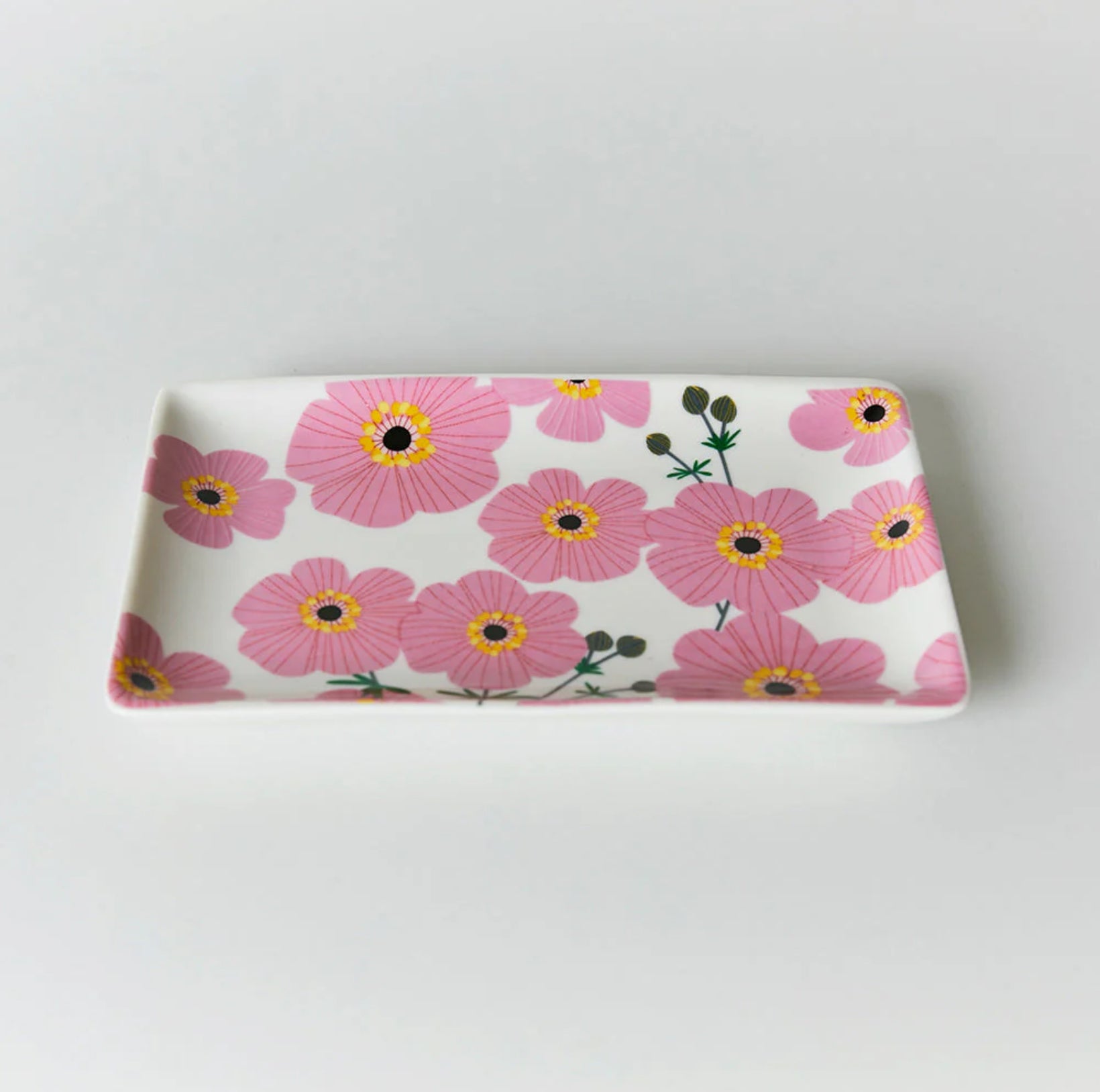 A rectangular pink trinket dish with a floral pattern of cosmos flowers.