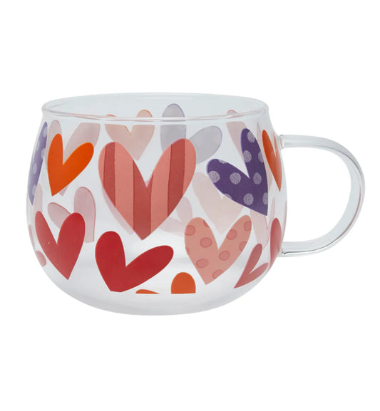 A glass mug with a wrap-around design featuring various shades of red and purple hearts, with a grey dot pattern and a silver handle.