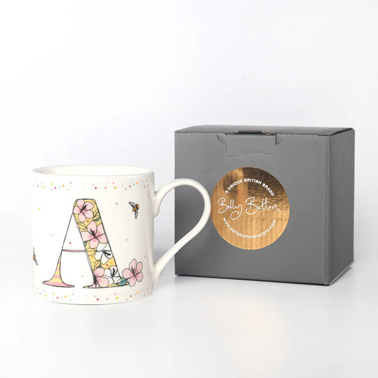 A white ceramic mug with a floral and animal pattern and the monogram 'A' on the front, accompanied by a grey presentation box with a foil stamp on the top.
