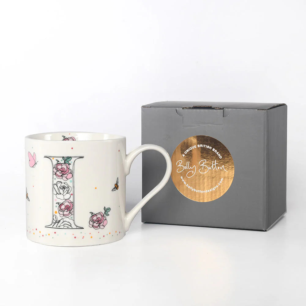 A white ceramic mug with a floral and insect pattern and a monogram initial 'I' design, accompanied by a grey presentation box with a foil stamp.