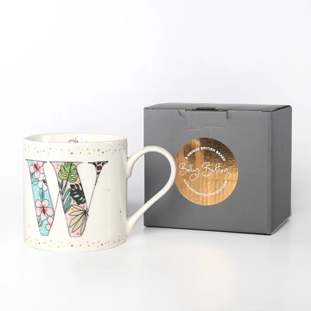 A white china mug with a multicolor floral pattern and the letter 'W' monogrammed in a decorative manner, accompanied by a grey presentation box with a foil stamp on the lid.