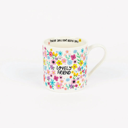 White ceramic mug with colorful floral pattern and the words “Lovely Friend” on the front, and the phrase “Thank you for being you” printed inside the rim.