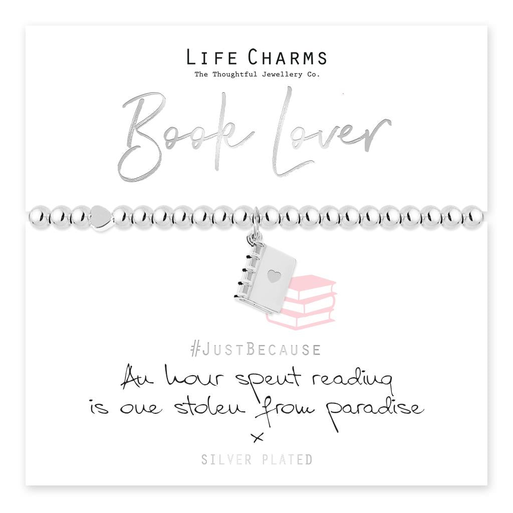 A silver-plated 3D book charm bracelet on a card, with the brand 'Life Charms' and the phrase 'Book Lover' displayed above. The card also includes a 'Just Because' message and a note stating the jewellery is silver plated.