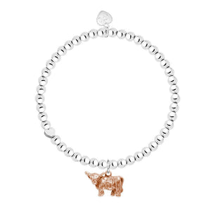 A rose gold plated highland cow charm on a bracelet with silver beaded stretch band.