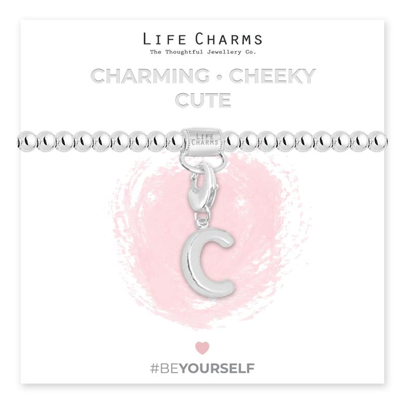 Initial charm bracelet with the letter C, presented on a silver foiled card with the text 'CHARMING • CHEEKY • CUTE' and the brand name 'LIFE CHARMS'. The bracelet is silver, and the card has a pink background with a heart shape.
